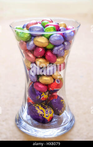 Mini huevos de Pascua de chocolate envuelto en envoltorios de aluminio de colores brillantes en un vaso de vidrio. Foto de stock