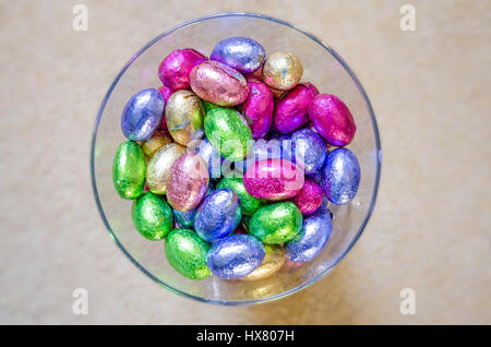 Mini huevos de Pascua de chocolate envuelto en envoltorios de aluminio de colores brillantes en un vaso de vidrio. Foto de stock