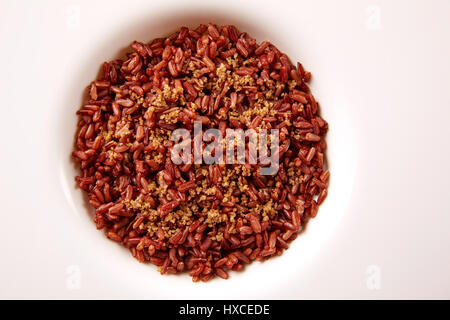 Rojo con arroz salvaje gomasio sésamo aderezos en una placa blanca sobre la plancha de madera Foto de stock