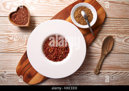 Rojo con arroz salvaje gomasio sésamo aderezos en una placa blanca sobre la plancha de madera Foto de stock