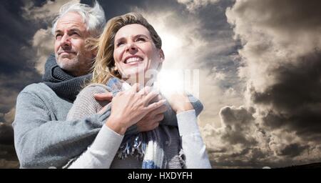 Compuesta Digital de pareja en ropa de invierno contra el cielo y los brillos