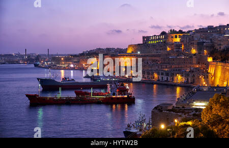 La vista de noche de Gran Puerto con los barcos de carga anclados cerca del baluarte de Santa Bárbara desde el inferior Barrakka Gardens, Valletta. Foto de stock