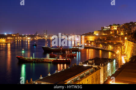 La vista de noche de Gran Puerto con los barcos de carga anclados cerca del baluarte de Santa Bárbara desde el inferior Barrakka Gardens, Valletta. Foto de stock
