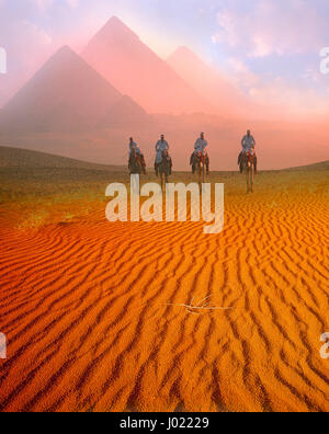 Pirámides y camelriders al amanecer, en Giza, Cairo, Egipto