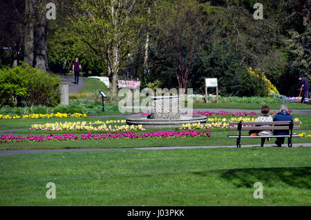Una pareja sentada en un banco del parque en Jardines del Valle en la ciudad balneario de Harrogate, Yorkshire.UK.