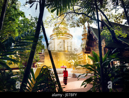 Mujer turista con rojo paraguas tradicional tailandés cerca de Golden templo Wat Phra Singh en Chiang Mai, Tailandia