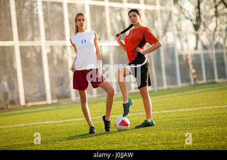 Aterrador de ahora en adelante mostrar Dos niñas en un uniforme de fútbol, de pie en un campo de fútbol con balón.  Llevan una camiseta, pantalones cortos, medias y botas de fútbol Fotografía  de stock - Alamy