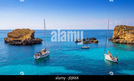 Comino, Malta - Barcos de vela en la hermosa Laguna Azul en la isla de Comino con turquesas aguas del mar, el cielo azul y las rocas en el agua
