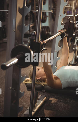 Ajuste y centrado joven mujer rubia en ropa para hacer ejercicio  sosteniendo una pesada barbell sobre su cabeza mientras trabajaba en un  gimnasio Fotografía de stock - Alamy