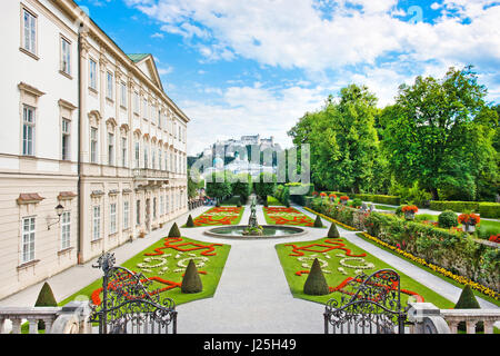 Hermosa vista de los conocidos Jardines de Mirabell con el palacio de Mirabell y el casco antiguo de la histórica fortaleza de Hohensalzburg en el fondo en Salzburgo, Austria Foto de stock