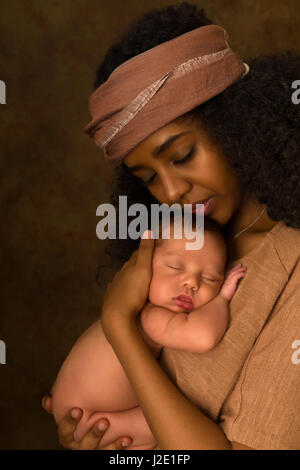 Madre joven etíope sostiene a su bebé de 7 días de edad poco contra un fondo oscuro