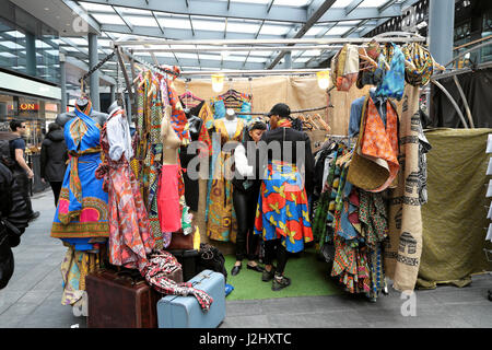 Un atractivo tall mujer trata sobre un africano vestido de impresión en Spitalfields Market, Londres, Reino Unido KATHY DEWITT Foto de stock
