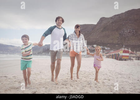 Retrato de familia, tomados de las manos mientras se ejecuta sobre la arena en la playa