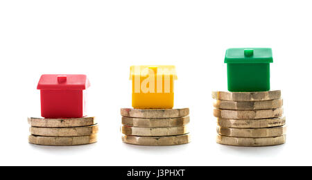 Tres casas sobre pilotes de nuevo pound monedas sobre un fondo blanco. Foto de stock