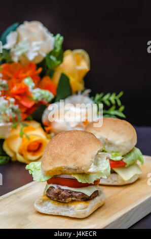 Deliciosos quesos gourmet hamburguesas caseras a base de carne con ingredientes frescos colocados en platos de madera Foto de stock