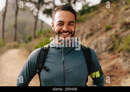 Retrato de caucásicos, joven y saludable hombre de pie afuera y sonriente. Seguros de machos jóvenes de la deslizadera en Country Road.