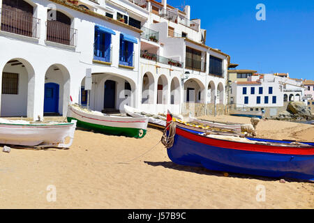 Algunos antiguos barcos pesqueros Barques varados en la playa de Calella de Palafrugell, Costa Brava, Cataluña, España, con sus características casas blancas wi Foto de stock