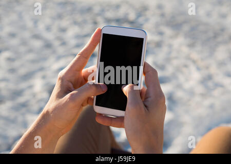 Recortada de manos del hombre a través de teléfono móvil en la playa
