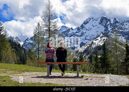 Dos mujeres sentadas en un banco y ver unas bonitas vistas a la montaña de los Alpes alemanes. Ubicación: panorama Rossfeldstrasse road, cerca de Berchtesgaden, Baviera, G
