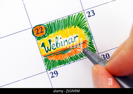 Mujer dedos con bolígrafo escrito Webinar recordatorio en el calendario. Foto de stock