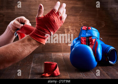 Hombre deportivas envolver su manos con guantes de boxeo y cinta de vendaje  sobre la plancha de madera. La foto en horizontal. Colorido equipo de boxeo.  Boxeo y formación Fotografía de stock 