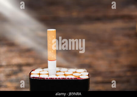 Cigarrillos y caja de cigarrillos con sun ray sobre fondo de madera Foto de stock