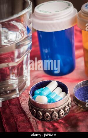Vintage metálico pastillero abierto con pastillas de color blanco a lo largo de un vidrio de agua Foto de stock