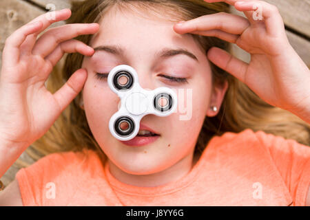 Adolescente femenina jugando con molestar spinner spinning juguete en su nariz modelo de liberación: Sí. Liberación de propiedad: No. Foto de stock