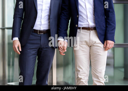 Dos hombres en trajes caminando y tomados de la mano Foto de stock