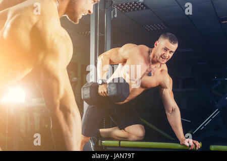 Muy power athletic guy , ejecutar el ejercicio con pesas de prensa en la sala de deportes Foto de stock