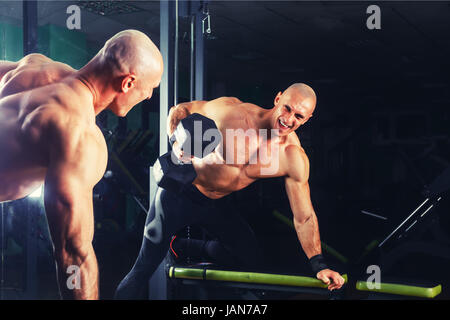 Muy power athletic guy , ejecutar el ejercicio con pesas de prensa en la sala de deportes Foto de stock