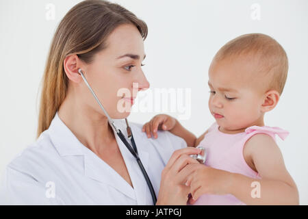 Doctor mirando al bebé mientras ella auscultating Foto de stock
