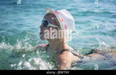 Hermosa mujer con gafas de sol nadando en una piscina