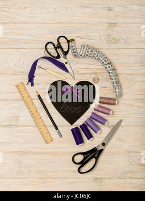 Accesorios de costura de color púrpura y el corazón con una inscripción - coser en el amor. El enfoque selectivo. Foto de stock