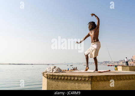 Un sadhu, hombre santo, baila sobre una plataforma en el río santo Ganges en meer ghat en el suburbio godowlia Foto de stock