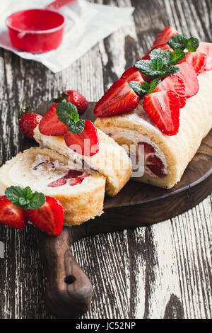Strawberry Shortcake tarta casera rollo con crema de queso crema batida, temporada de verano perfecto postre servido en placa de madera rústica Foto de stock