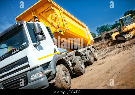 Camión volquete en constrution industrial sitio esperando por la carga de masa de la excavadora Foto de stock