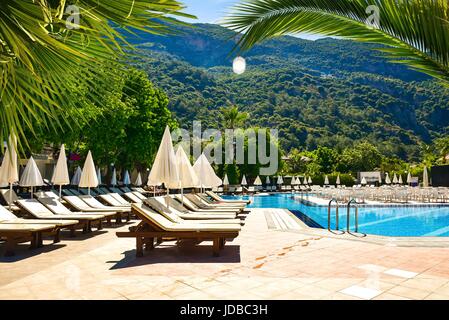 Sunny Hotel Resort de lujo con piscina de color azul, palmeras, sombrillas y hamacas en Turquía. Ricos en el complejo de vacaciones soleadas.