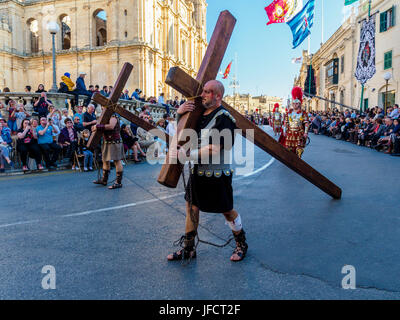 Habitantes de Zejtun / Malta tuvo su tradicional procesión del Viernes santo en frente de su iglesia, dos de ellos, que llevaba una cruz Foto de stock