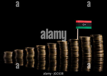 Bandera de Libia, con un montón de monedas aislado sobre fondo negro Foto de stock