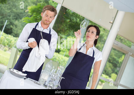 Macho y hembra camarero secando vasos de vino Foto de stock
