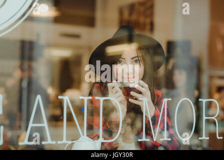 Retrato de mujer joven sentado en la cafetería, ver a través de la ventana Foto de stock