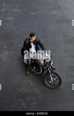 Vista superior de un jinete apuesto hombre de negro biker chaqueta, camisa a  cuadros, jeans y botas sentarse en estilo clásico cafe racer moto. Moto  custom made Fotografía de stock - Alamy