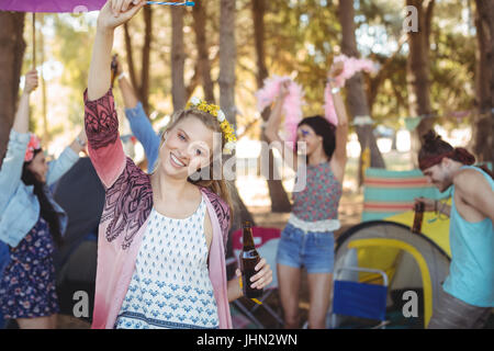Retrato de mujer sonriente levantando la mano con sus amigos en el fondo disfrutando a camping Foto de stock