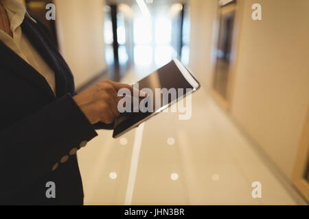 Sección media de la empresaria con tablet PC mientras está de pie en el pasillo Foto de stock