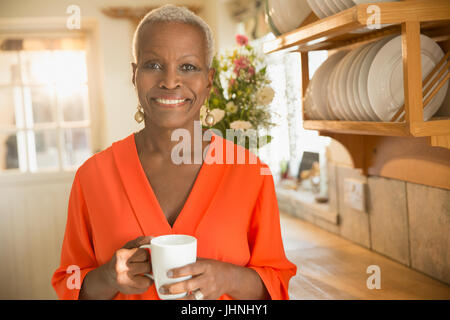 Retrato sonriente mujer senior beber café en la cocina Foto de stock