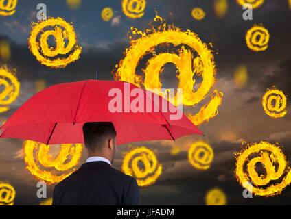 Compuesta digital de imagen digital del empresario sosteniendo la sombrilla roja de pie en medio de la quema a símbolo Foto de stock