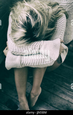 Miserable joven sentada en el suelo llorando Foto de stock