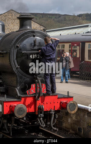 Conductor de tren en la parte delantera de la locomotora a vapor, BR (ferrocarril Midland) 4F 0-6-0 43924, detenido en la estación - Keighley y Worth Valley Railway, Inglaterra, Reino Unido. Foto de stock