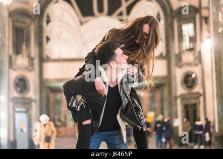 El hombre lleva una mujer caucásica piggyback en el vestíbulo